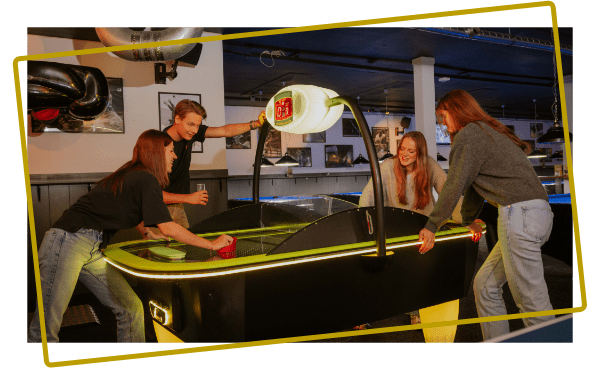 Vrienden spelen airhockey in de sportsbar bij Kings & Queens in Assen