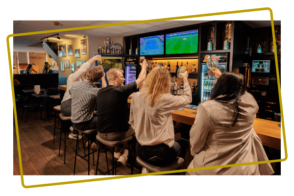 Groep vrienden proost aan de bar in de Sportsbar van Kings en Queens Assen
