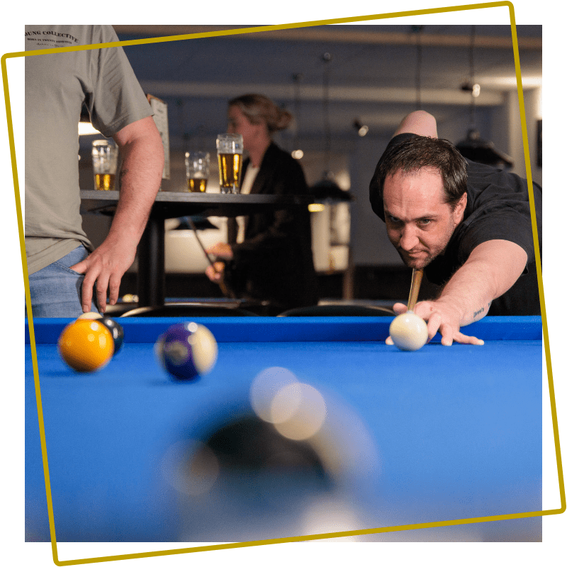 Speler richt op de witte bal tijdens het poolen in Assen