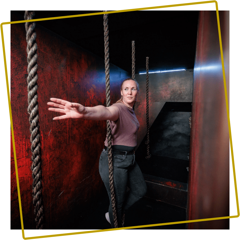 Vrouw manoeuvreert tussen touwen in een uitdagende kamer van Prison Island bij Kings en Queens Assen