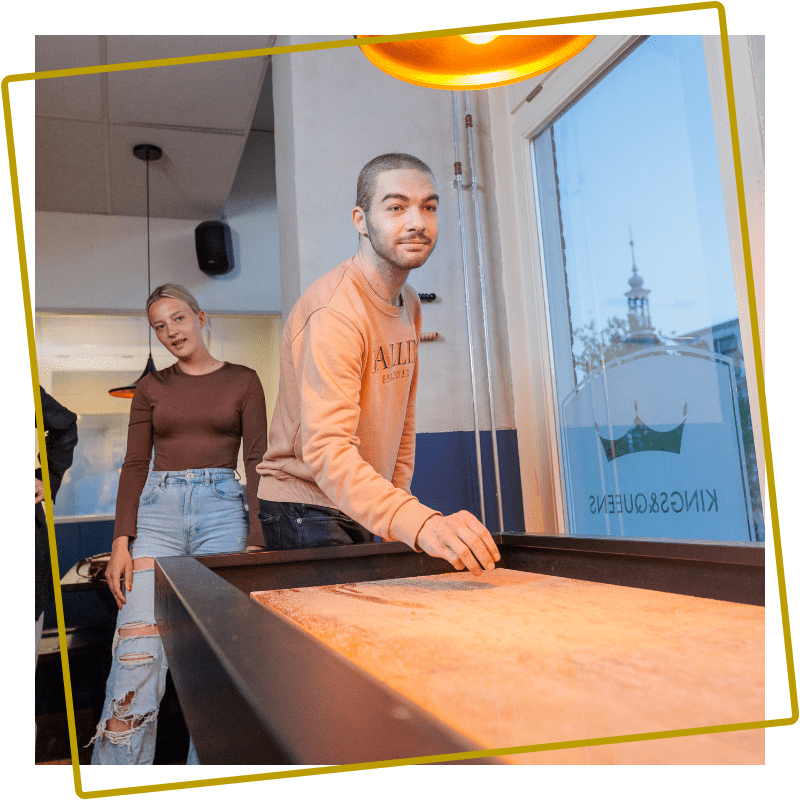 Man speelt shuffleboard bij Kings & Queens in Assen